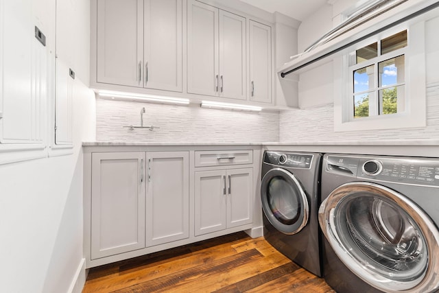 clothes washing area featuring washer and clothes dryer, dark wood finished floors, and cabinet space