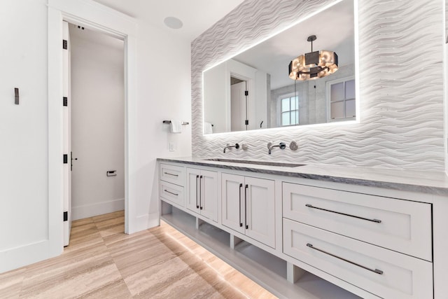 bathroom featuring a chandelier, tasteful backsplash, vanity, and baseboards