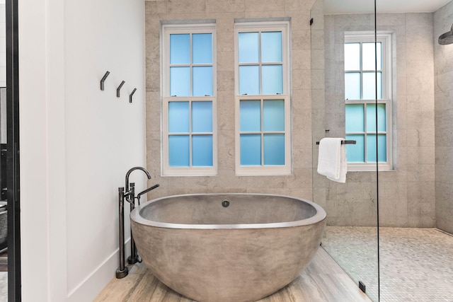 bathroom with a soaking tub, baseboards, and walk in shower