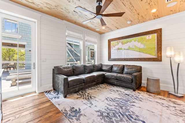 living area featuring wooden ceiling, hardwood / wood-style floors, a ceiling fan, and wood walls