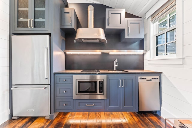 kitchen with stainless steel appliances, a sink, vaulted ceiling, dark wood-style floors, and glass insert cabinets