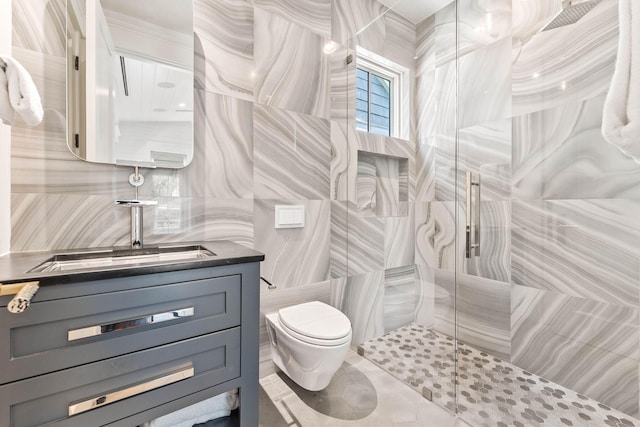 bathroom featuring a shower with door, toilet, vanity, tile walls, and tile patterned flooring