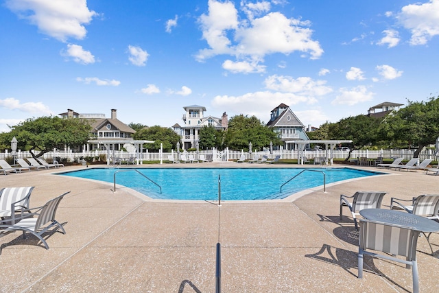 community pool featuring fence and a patio