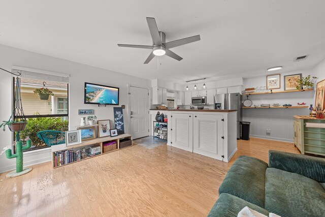 living area with a ceiling fan, light wood-style floors, and baseboards