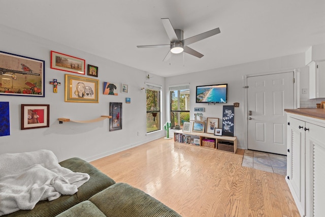 living room with a ceiling fan, light wood finished floors, and baseboards