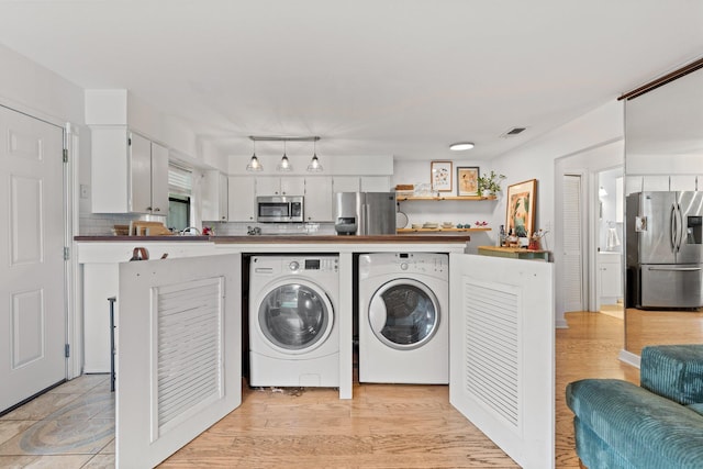 laundry area featuring washer and clothes dryer and light wood finished floors
