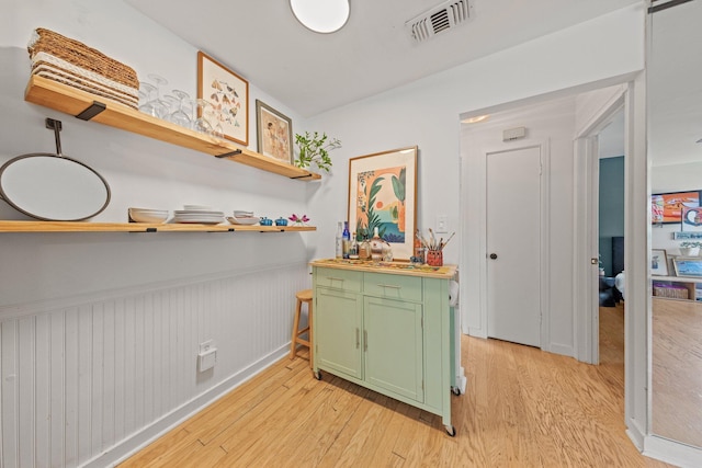hall featuring light wood finished floors, a wainscoted wall, and baseboards