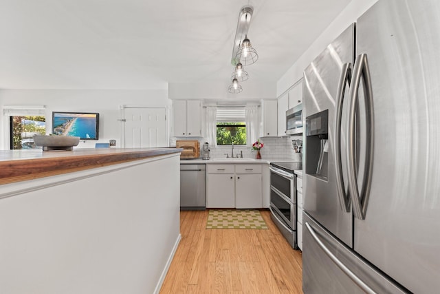 kitchen with appliances with stainless steel finishes, a sink, white cabinetry, and light wood finished floors