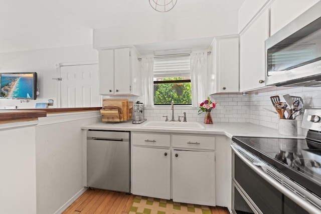 kitchen featuring stainless steel appliances, a sink, white cabinets, light countertops, and tasteful backsplash