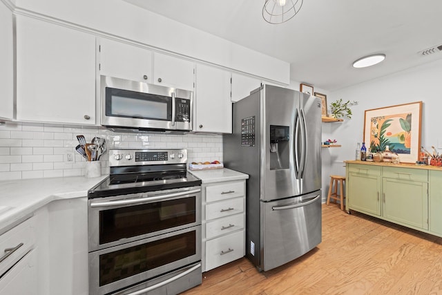 kitchen featuring stainless steel appliances, light countertops, light wood finished floors, and tasteful backsplash