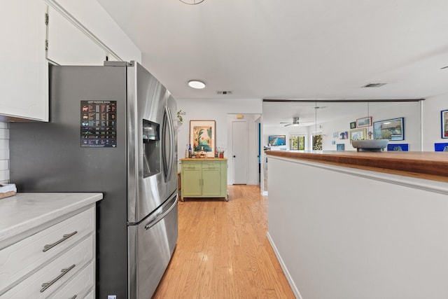 kitchen featuring stainless steel fridge with ice dispenser, light wood-type flooring, ceiling fan, white cabinetry, and butcher block counters