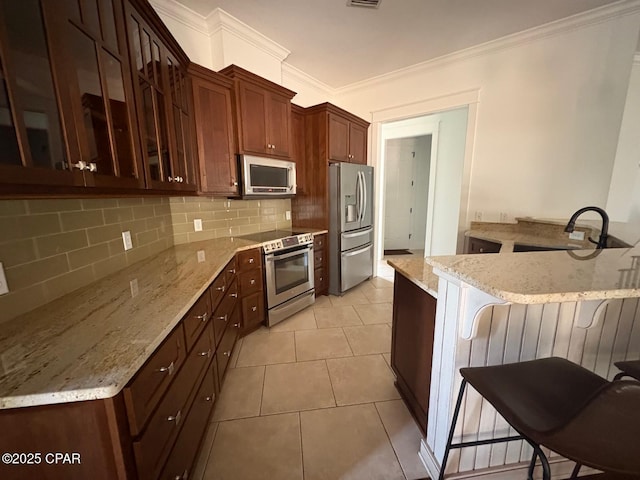 5303 Hopetown Ln, Panama City Beach, FL 32408 - kitchen featuring stainless steel appliances, a breakfast bar area, ornamental molding, backsplash, and glass insert cabinets