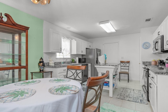 102 Wright Dr, Niceville, FL 32578 - kitchen with stainless steel appliances, white cabinetry, light tile patterned floors, and stone countertops