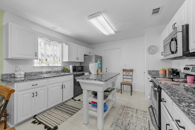 102 Wright Dr, Niceville, FL 32578 - kitchen with black appliances, a sink, white cabinets, dark stone counters, and light tile patterned floors