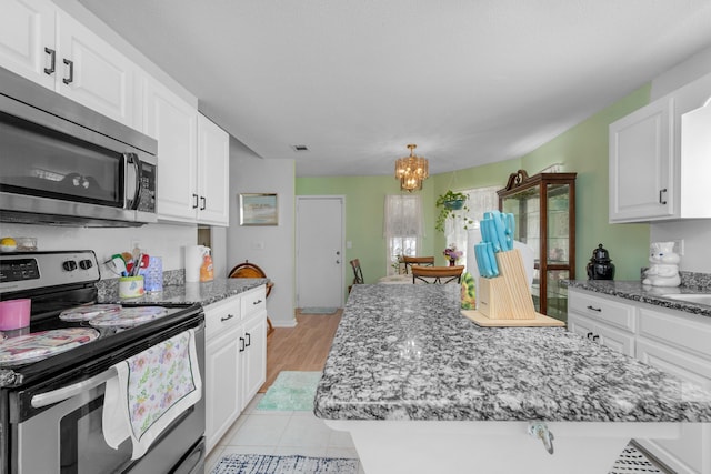 102 Wright Dr, Niceville, FL 32578 - kitchen featuring appliances with stainless steel finishes, white cabinetry, a chandelier, and dark stone counters