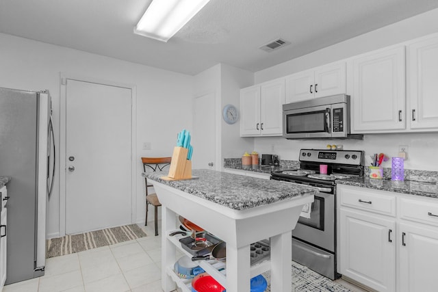 102 Wright Dr, Niceville, FL 32578 - kitchen with stainless steel appliances, white cabinets, light stone counters, and a textured ceiling