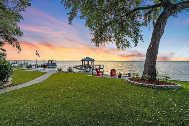 411 Calhoun Ave, Destin, FL 32541 - yard at dusk with boat lift, a lawn, a water view, and a dock