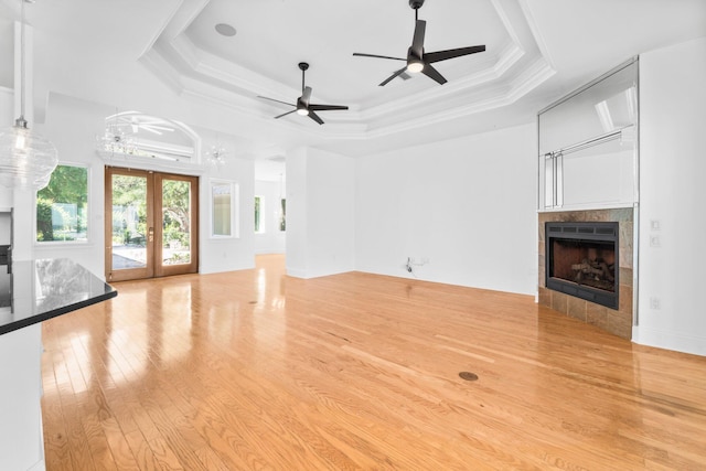 411 Calhoun Ave, Destin, FL 32541 - unfurnished living room featuring a tiled fireplace, light wood finished floors, a ceiling fan, a raised ceiling, and crown molding