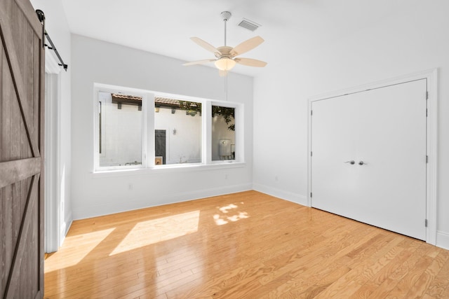 411 Calhoun Ave, Destin, FL 32541 - unfurnished bedroom with a barn door, wood finished floors, baseboards, and ceiling fan