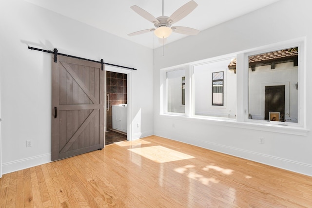 411 Calhoun Ave, Destin, FL 32541 - unfurnished bedroom with a barn door, wood finished floors, baseboards, and connected bathroom