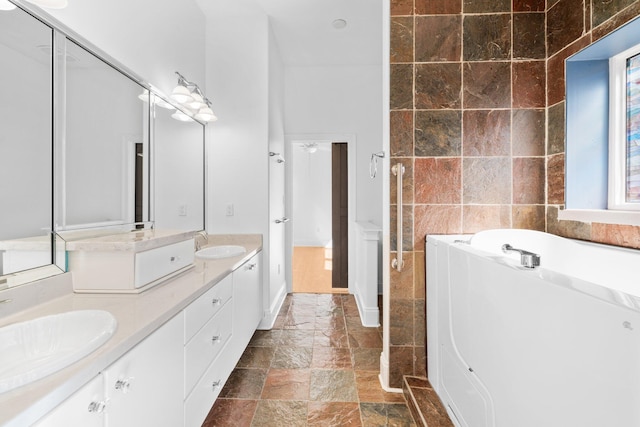 411 Calhoun Ave, Destin, FL 32541 - bathroom with double vanity, a garden tub, stone tile floors, and tile walls