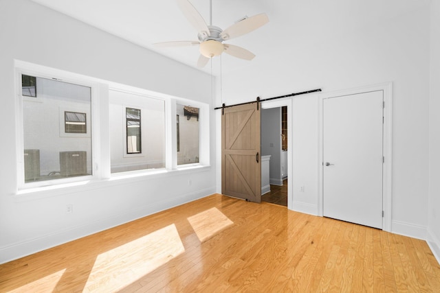 411 Calhoun Ave, Destin, FL 32541 - unfurnished bedroom with wood finished floors, baseboards, a barn door, and a ceiling fan