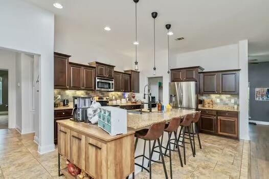 5930 Wind Trace Rd, Crestview, FL 32536 - kitchen with appliances with stainless steel finishes, backsplash, a sink, dark brown cabinetry, and a large island