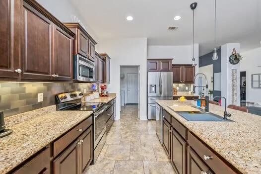 5930 Wind Trace Rd, Crestview, FL 32536 - kitchen with appliances with stainless steel finishes, a sink, backsplash, pendant lighting, and light stone counters