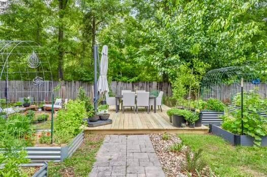 5930 Wind Trace Rd, Crestview, FL 32536 - fenced backyard with a vegetable garden, outdoor dining area, and a wooden deck