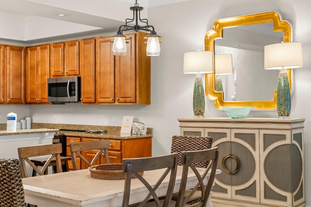 1653 W County Highway 30a Unit 1109, Santa Rosa Beach, FL 32459 - kitchen featuring stainless steel microwave, brown cabinets, light stone countertops, and pendant lighting