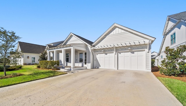 view of front of home with board and batten siding, concrete driveway, a garage, a front lawn, and covered porch