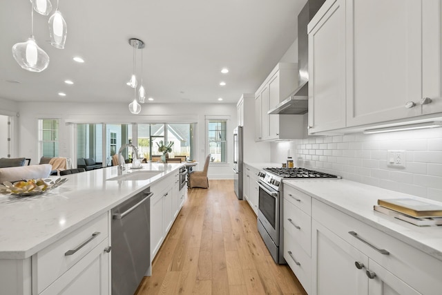 kitchen with appliances with stainless steel finishes, a sink, light wood-type flooring, white cabinets, and recessed lighting