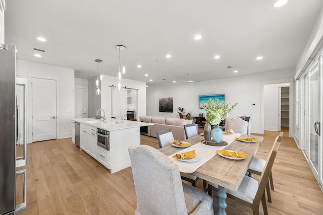 dining room with light wood finished floors, a barn door, recessed lighting, and baseboards