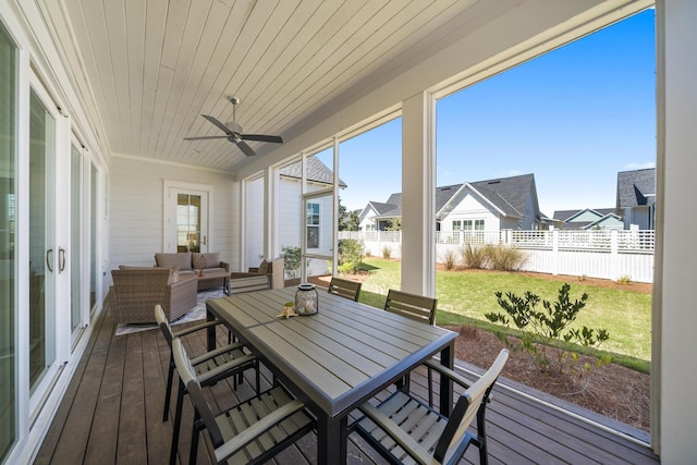 sunroom with ceiling fan, outdoor dining space, outdoor lounge area, and a residential view