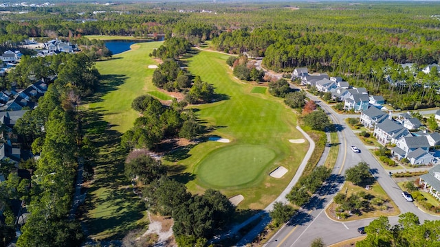 view of property location featuring a golf club, a heavily wooded area, a nearby body of water, and nearby suburban area