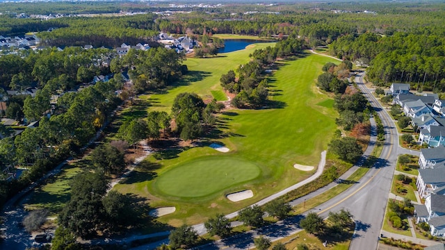 aerial view of property and surrounding area featuring a local golf course, a large body of water, a forest, and nearby suburban area