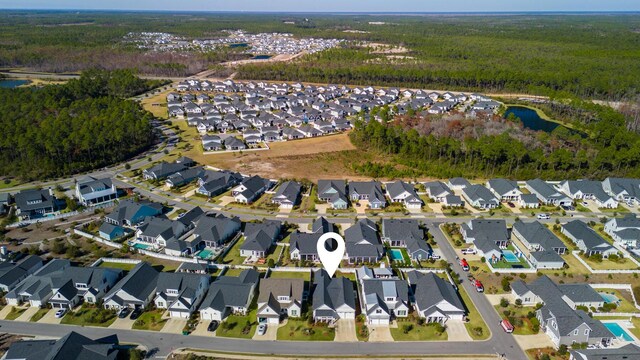 aerial view of property and surrounding area with a forest, a nearby body of water, and nearby suburban area