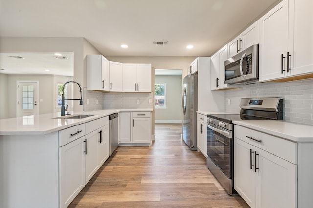 1411 28th St, Niceville, FL 32578 - kitchen with appliances with stainless steel finishes, a sink, a peninsula, light wood-style flooring, and backsplash