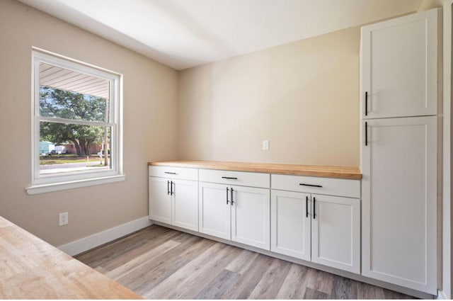 1411 28th St, Niceville, FL 32578 - kitchen with light wood-style floors, wood counters, white cabinetry, and baseboards