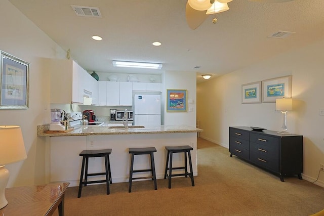 2606 Scenic Gulf Dr Unit 4108, Miramar Beach, FL 32550 - kitchen with freestanding refrigerator, a peninsula, light colored carpet, white cabinetry, and a breakfast bar area