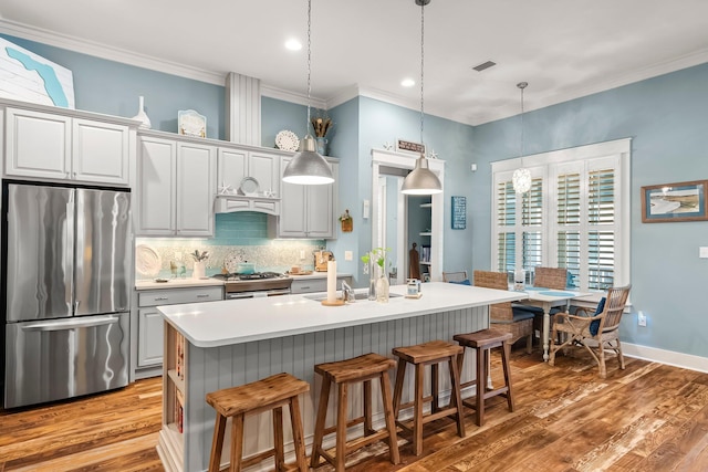 728 Breakers St, Watersound, FL 32461 - kitchen featuring stainless steel appliances, wood finished floors, decorative backsplash, crown molding, and a kitchen breakfast bar