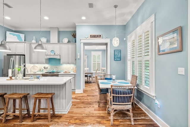 728 Breakers St, Watersound, FL 32461 - kitchen with freestanding refrigerator, light wood-type flooring, pendant lighting, tasteful backsplash, and a kitchen bar