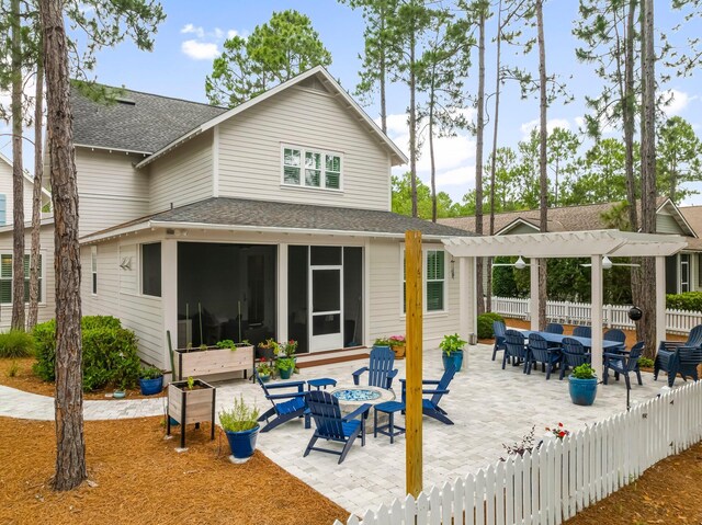 728 Breakers St, Watersound, FL 32461 - rear view of property featuring a sunroom, a shingled roof, a patio area, and a fire pit
