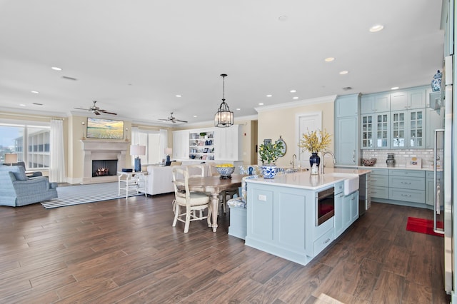 134 Norwood Dr Ph 3, Miramar Beach, FL 32550 - kitchen with open floor plan, a sink, a warm lit fireplace, crown molding, and a center island with sink