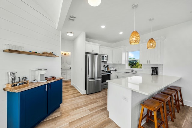 216 E Park Place Ave, Inlet Beach, FL 32461 - kitchen with appliances with stainless steel finishes, blue cabinetry, a sink, a breakfast bar, and a peninsula