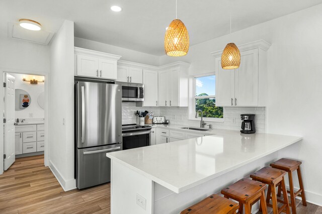 216 E Park Place Ave, Inlet Beach, FL 32461 - kitchen with appliances with stainless steel finishes, a sink, a peninsula, a breakfast bar area, and white cabinets