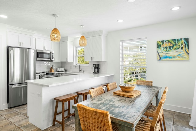 216 E Park Place Ave, Inlet Beach, FL 32461 - kitchen featuring appliances with stainless steel finishes, a sink, decorative backsplash, a peninsula, and white cabinetry
