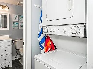 308 Miracle Strip Pkwy Unit 1C, Fort Walton Beach, FL 32548 - laundry room with stacked washer / dryer and dark wood-style flooring