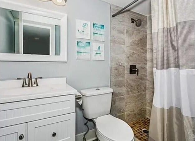 308 Miracle Strip Pkwy Unit 1C, Fort Walton Beach, FL 32548 - bathroom featuring a tile shower, vanity, and toilet