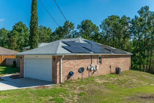 430 Hatchee Dr, Crestview, FL 32536 - view of side of property with a garage, solar panels, concrete driveway, a yard, and brick siding